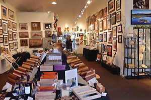 Gallery interior with multiple framed paintings hanging on the walls.