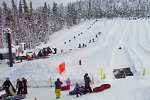 Tubing lanes with people coming off a run in the foreground and people lined up to start a run in the background.
