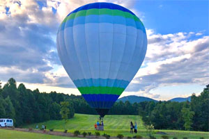 Hot air balloon on tethered on grass field.