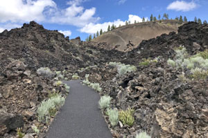 Paved "Trail of the Molten Land" winding through lava flow formations with Lava Butte in the background.