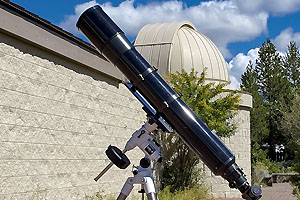 Telescope on tripod outside the dome of the Oregon Observatory building.