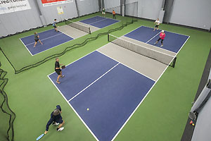Tow indoor pickleball courts with doubles players on each court.