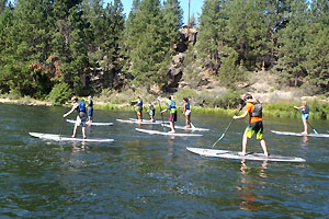 Group of people stand up paddle boarding on the Deschutes River.