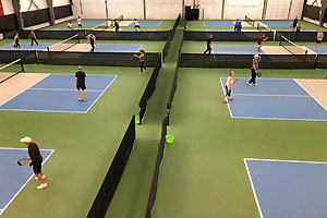 Widgi Creek pickleball courts with several players engaged in singles play.