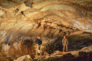 Explorers inside lighted lava tube cave.