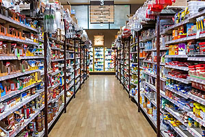 Interior aisle with shelves of products down both sides and coolers in the background.